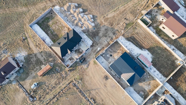 An aerial view of a new housing development under construction, showing multiple houses in various stages of completion. Construction equipment and workers are visible, emphasizing the ongoing building activity.